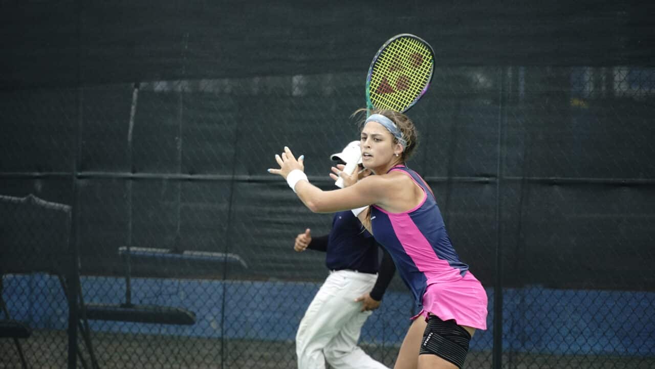 Carolina Meligeni, vestindo azul e rosa, prepara-se para atacar a bola no ITF W25 de Guayaquil