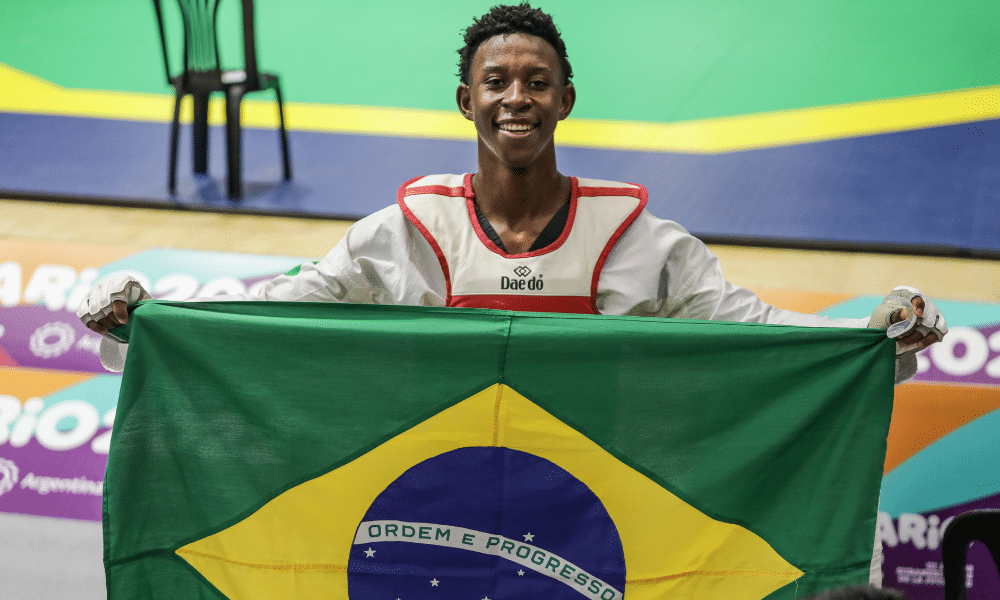 Henrique Fernandes segura a bandeira do Brasil após ouro no taekwondo em Rosario 2022