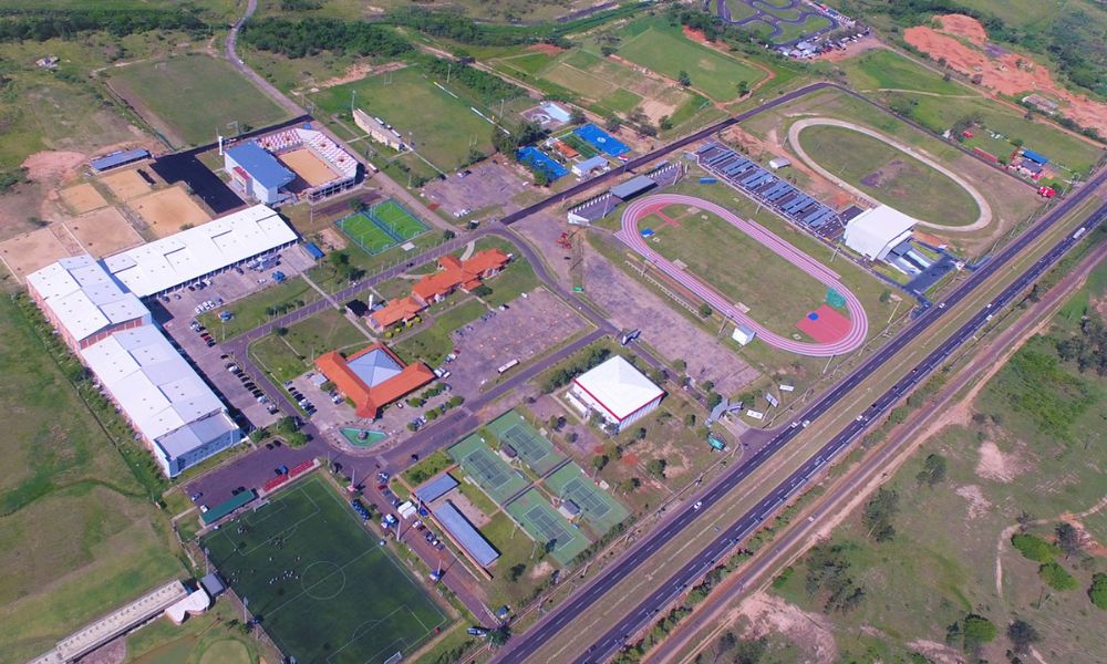 Panorama do Parque Olímpico de Assunção-2022 com quadras de tênis, de areia, pista de atletismo, quadras de tênis e campos de futebol e rugby.
