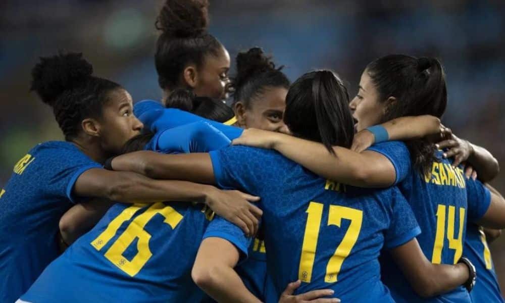 Brasil: atletas da seleção feminina se abraçam. Elas vestem camisa azul com números em amarelo