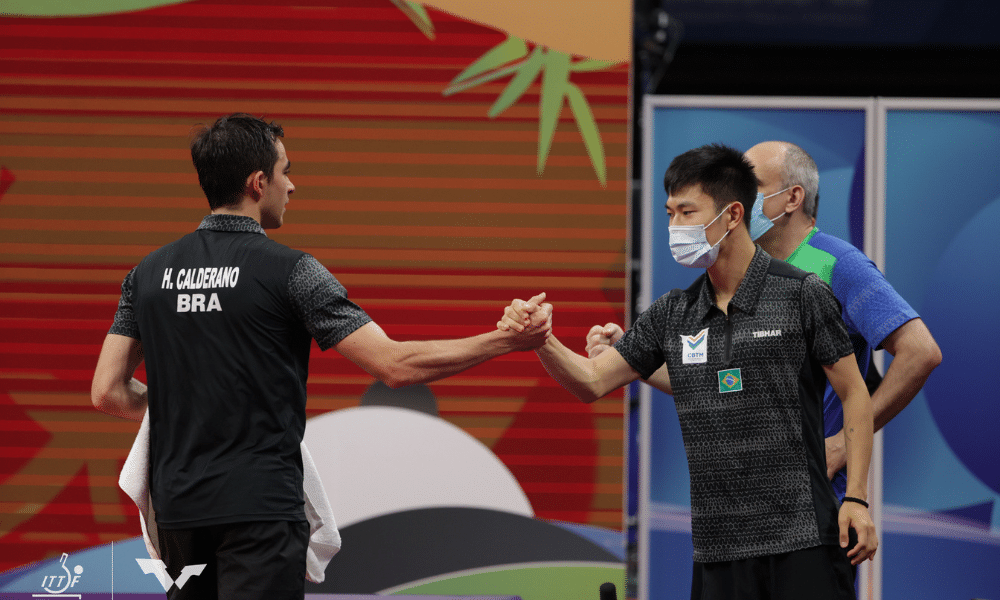 Calderano e Jouti se cumprimentam no Mundial por equipes de tênis de mesa Portugal