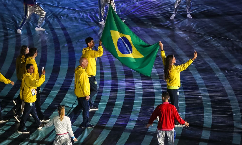Nathalie Moellhausen e Guilherme Costa com a bandeira do Brasil na abertura de Assunção-2022