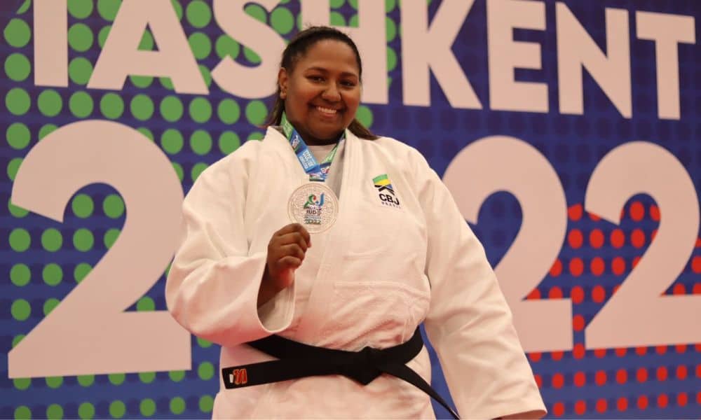 Beatriz Souza posa para foto de judogi branco e segurando sua medalha de prata