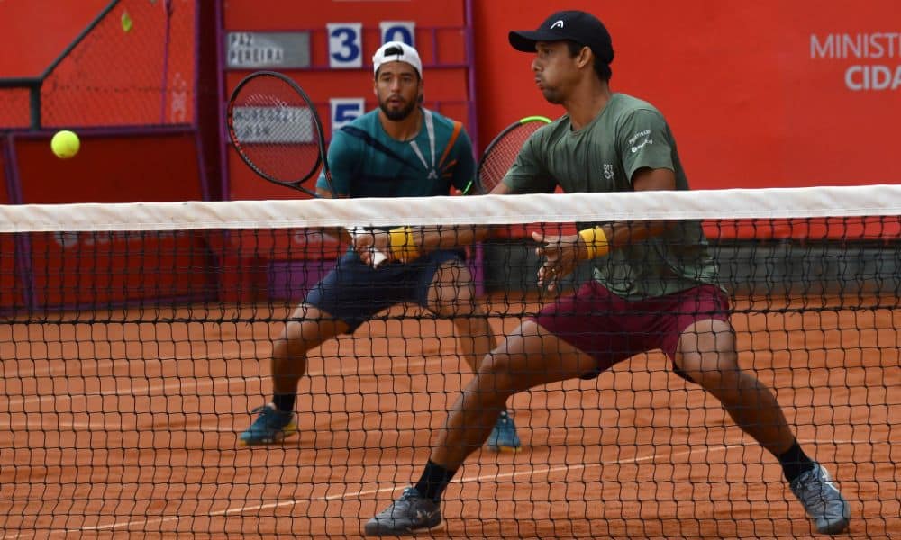 Challenger de Campinas: Zé Pereira na rede devolvendo bola com a raquete. Paz aparece no fundo