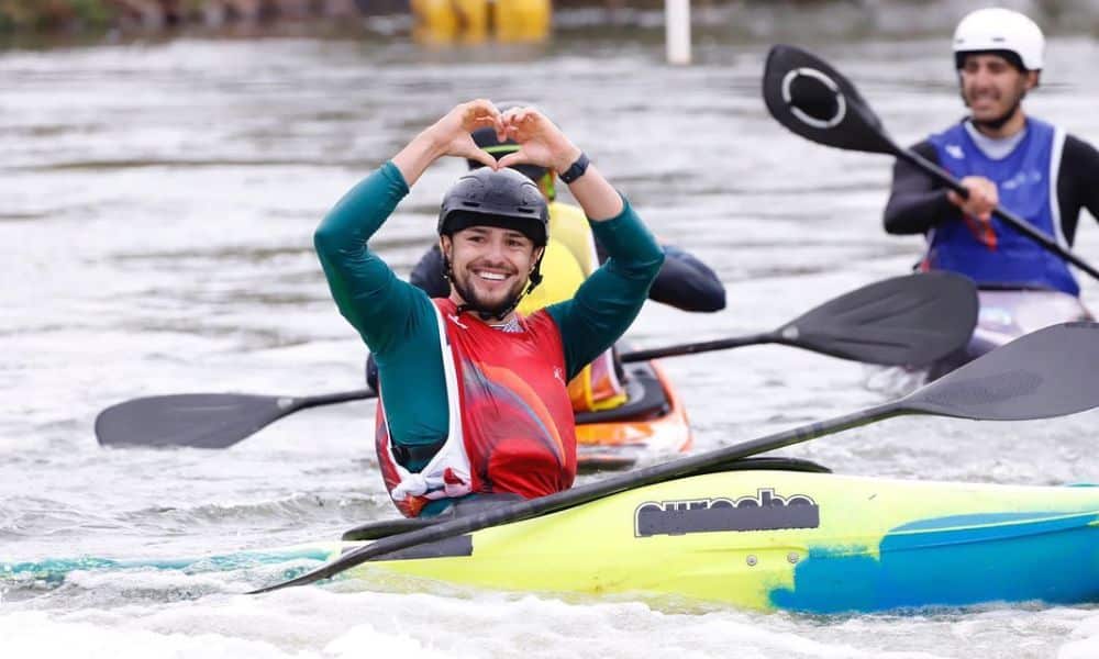 Pepê Gonçalves dentro do seu kayak faz um coraçãozinho com as mãos em cima da sua cabeça
