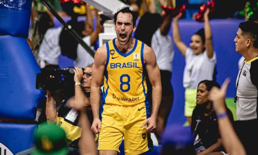 seleção masculina de basquete: Vitor Benite grita na quadra. Ele veste uniforme todo amarelo do Brasil com o número 8
