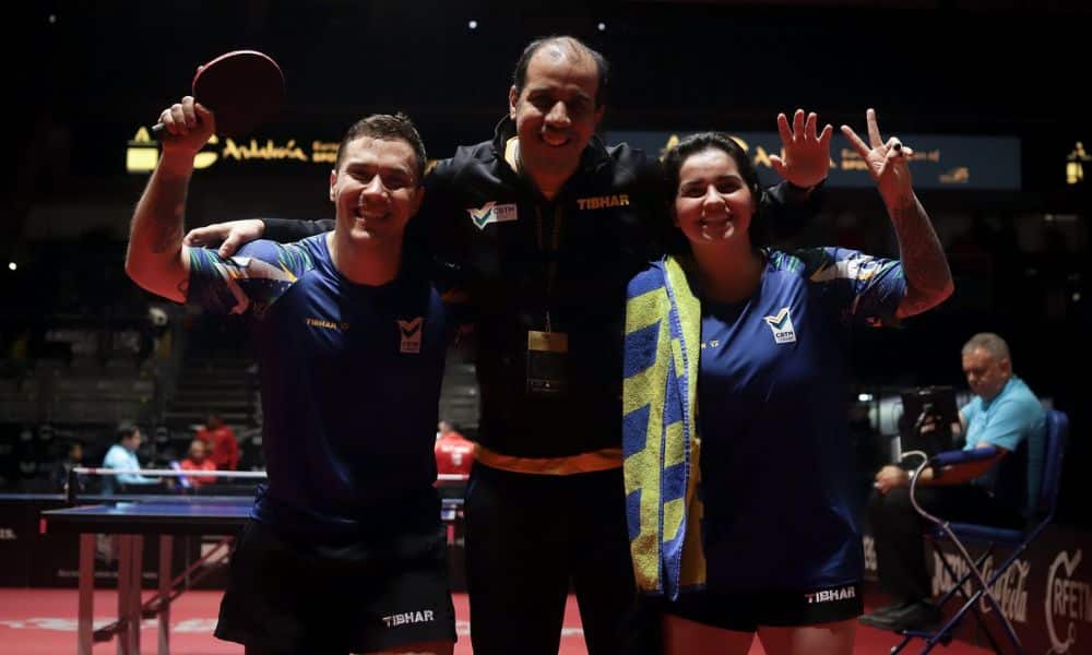 Paulo Salmin e Bruna Alexandre posam para foto com um dos treinadores do Brasil