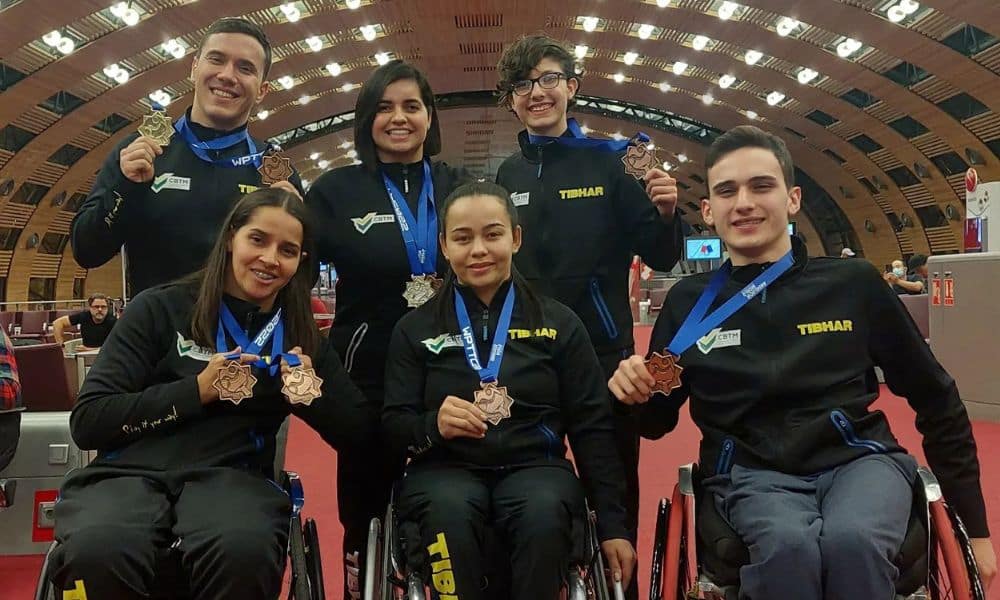 Brasil no tênis de mesa - seis atletas (três sentados e três em pé) posam para fotos segurando suas medalhas