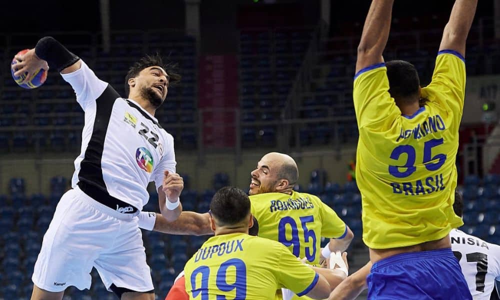 Brasil no handebol - Jogador da Tunísia aremmessa a enquanto brasileiro ergue os braços para bloqueá-la