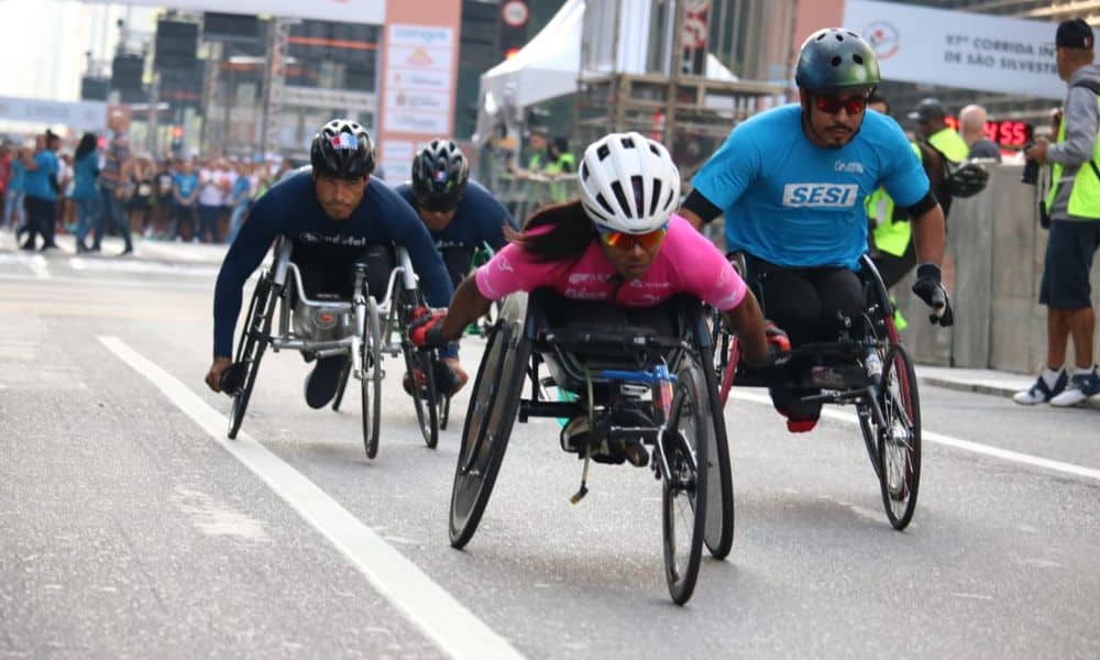 São Silvestre - Vanessa Cristina conduz sua cadeira de rodas na Avenida Paulista. Carlos Nascimento e outros dois atletas a perseguem ao fundo