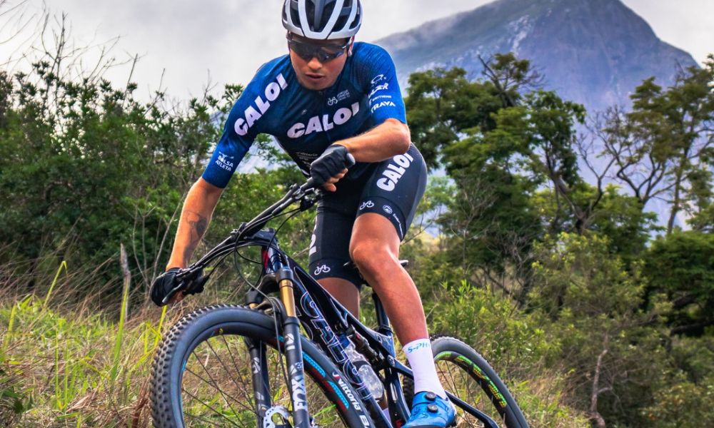 Ulan Galinski, atleta do ciclismo mountain bike, desce em caminho no meio do mato
