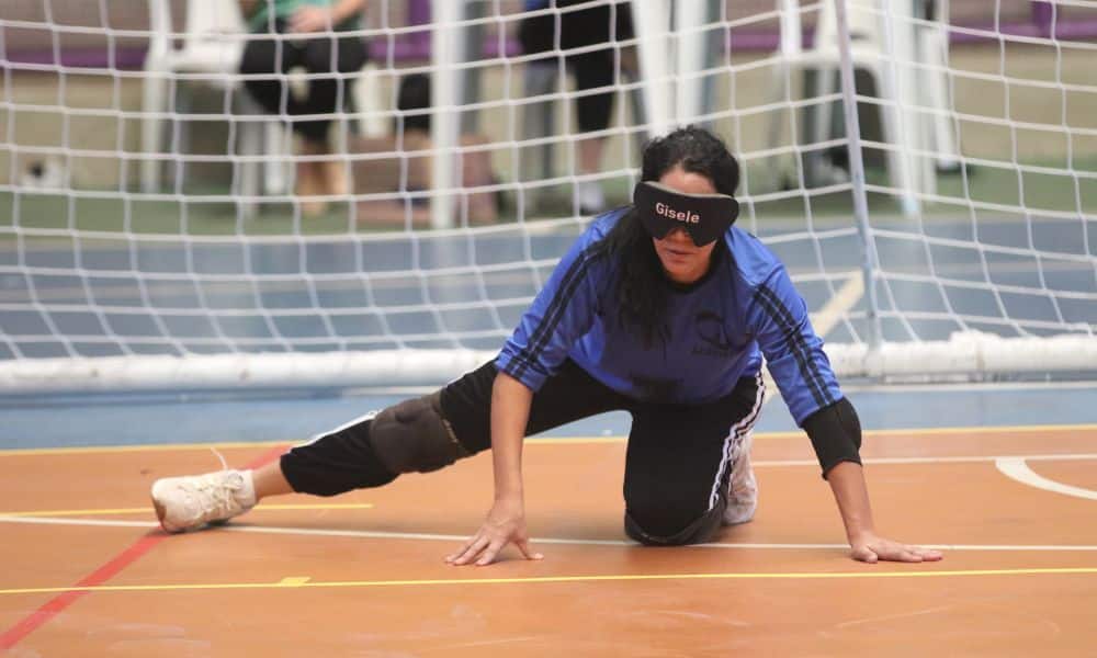 Atleta Gisele, da Adevibel, se apoia na quadra com o joelho para proteger o gol em jogo do Regional Sudeste 1 de goalball