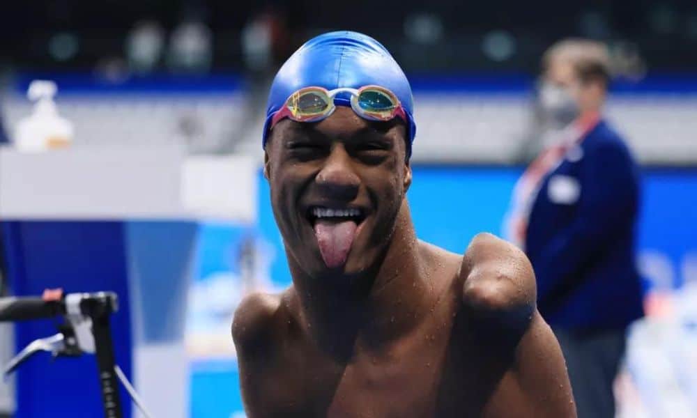 Mas Gabrielzinho Araújo com touca azul e óculos de natação. Ele coloca a língua para fora / Mundial de Natação Paralímpica