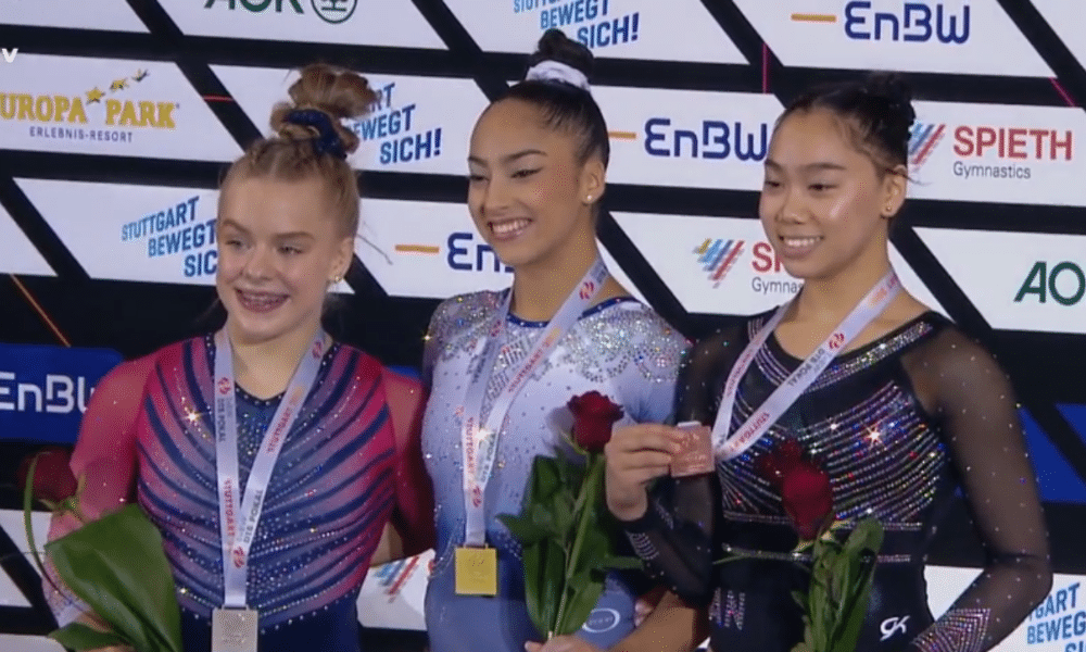 Mas Joscelyn, Júlia e Aurélie no pódio com suas medalhas no peito. Elas carregam flores mas