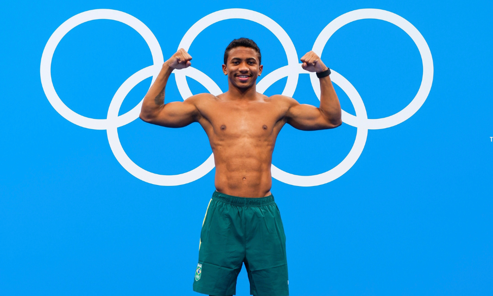 Isaac Souza enquanto faz pose em frente aos aros olímpicos Mundial