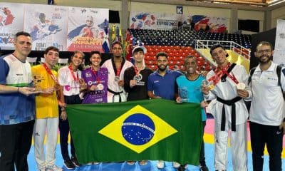 Atletas e membros da comissão posam com medalhas e uma bandeira do Brasil Aberto Dominicano de taekwondo