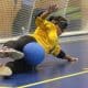 Jéssica estica as pernas na posição de chicote e faz a defesa durante treino; ela veste camisa de manga longa amarela da Seleção e calça preta (Renan Cacioli/ CBDV)