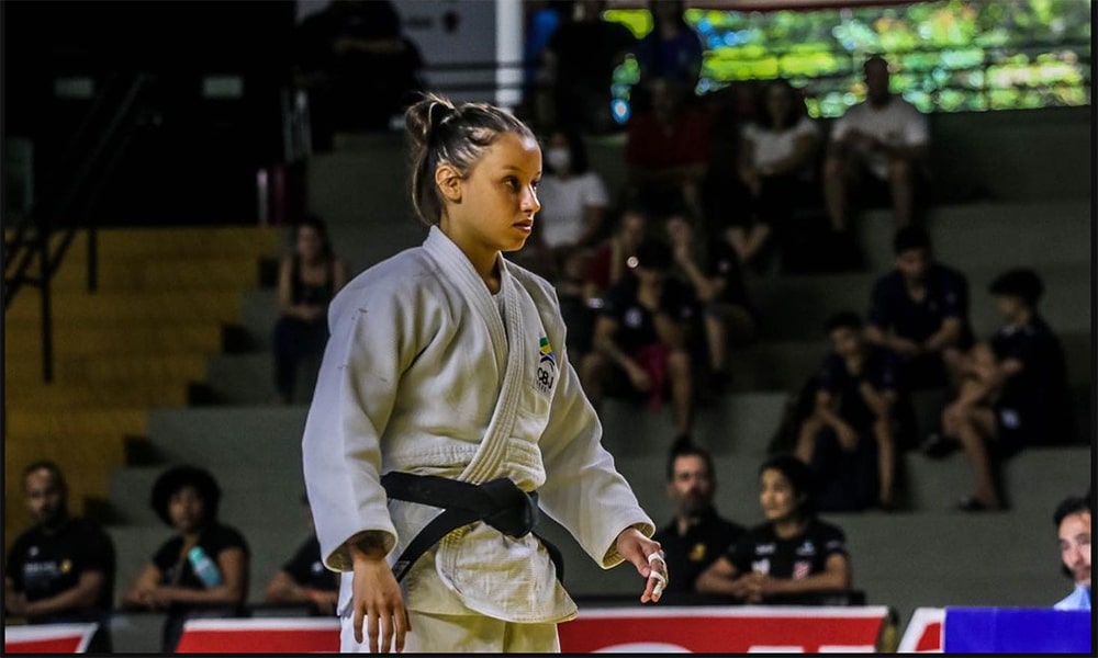 Na imagem, Natasha Ferreira concentrada, de kimono branco, antes da luta.