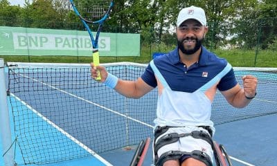 Daniel Rodrigues posa para foto ao lado da rede. Ele está em sua cadeira de rodas e segura a raquete com a mão direita