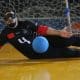Atleta do IRM faz defesa no Regional Sul de goalball. Ele veste um uniforme todo preto, com detalhes em vermelho. A bola é azul