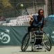Ymanitu Silva em quadra pelo Brasil na Copa do Mundo de tênis em cadeira de rodas. Eles está em sua cadeira e ataca a bola com a mão direita