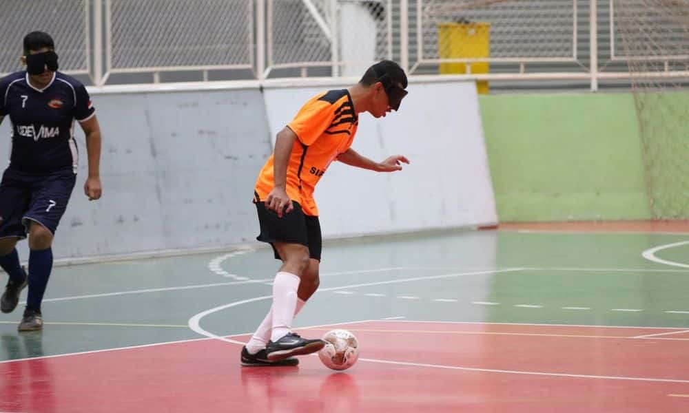 Raynã conduz a bola, com um marcador mais afastado à esquerda da imagem. Atleta veste camisa laranja com detalhes em preto, da Acelgo, calção preto e meiões brancos (Renan Cacioli/CBDV)