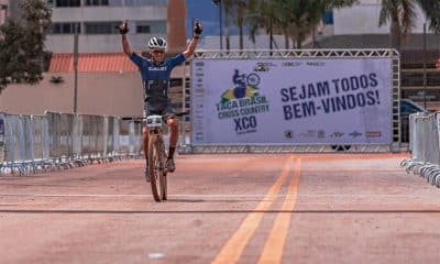 Na imagem, Ulan Galinski em cima de sua bicicleta, comemorando a vitória na linha de chegada.