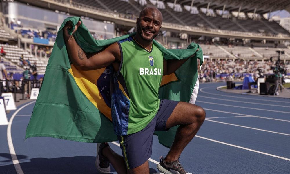João Victor Teixeira ajoelhado e com a bandeira do Brasil após medalha no Mundial