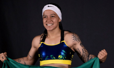 Bia Ferreira sorridente enquanto segura bandeira do Brasil na luta do boxe profissional