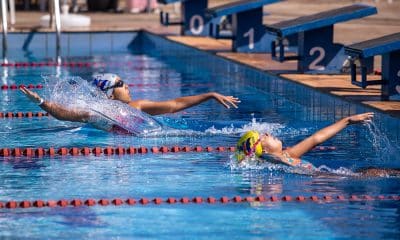 Na imagem, momento de duas atletas largando na piscina para disputar a prova.