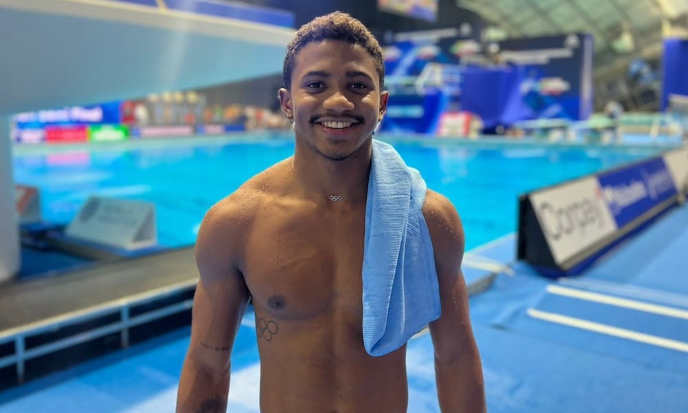 Isaac Souza posa para foto com as plataformas de saltos ao fundo