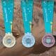 Na imagem, as medalhas dos Jogos Pan-Americanos de Santiago 2023, com uma mineradora ao fundo.