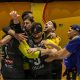Jogadores e comissão técnica do Athlon se abraçam, emocionados, em comemoração à vitória no Brasileiro de goalball. Eles estão na quadra e há um fundo amarelo (Foto: Taba Benedicto/CBDV)