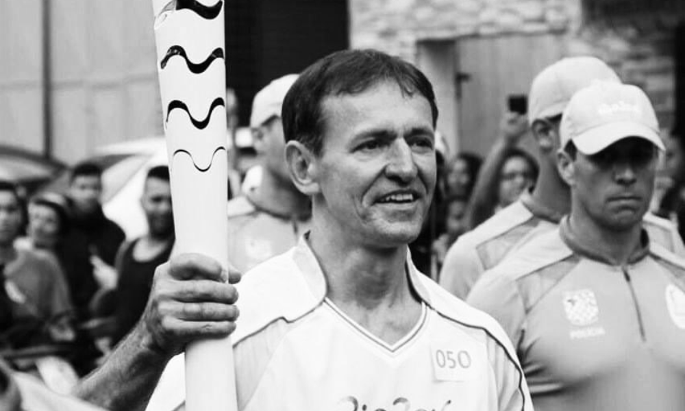 Foto em preto e branco de João Luiz Ribeiro com tocha olímpica da Rio-2016