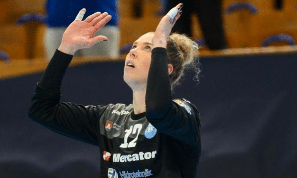 Babi Arenhart, goleira do Krim Mercator, ergue as mãos para o céu em partida da Champions League de handebol feminino