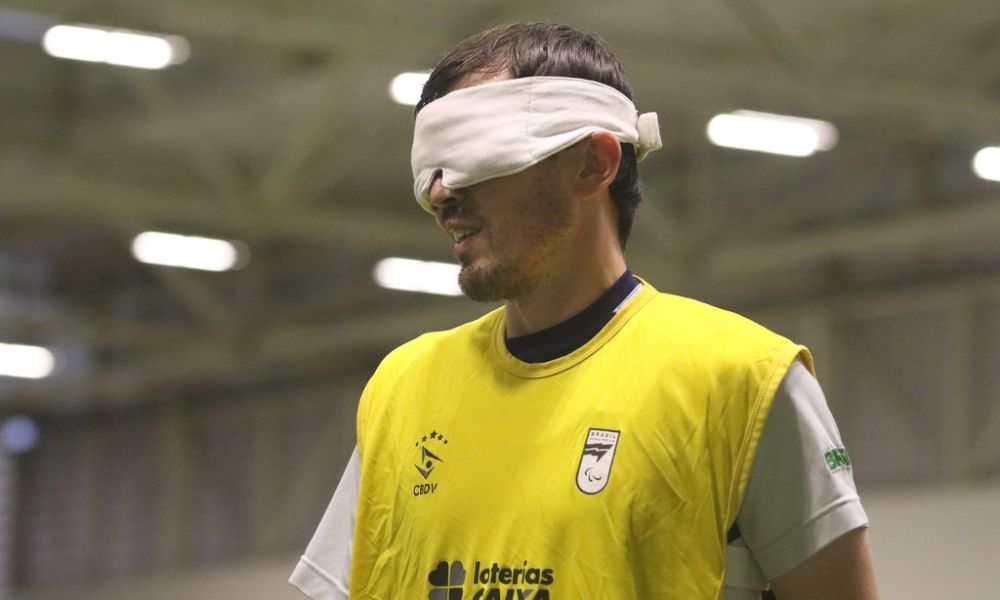 Foto fechada no rosto de Ricardinho, que usa venda branca tapando os olhos e colete amarelo de treino (Foto: Renan Cacioli/CBDV)