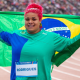 Izabela Rodrigues da Silva com bandeira do Brasil nas costas após medalha de ouro no lançamento de disco em Santiago-2023