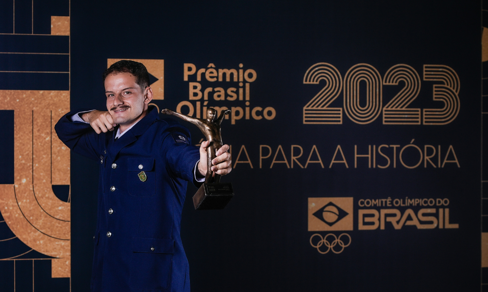 Marcus D'Almeida faz pose de tiro com arco segurando o Troféu Rei Pelé no Prêmio Brasil Olímpico