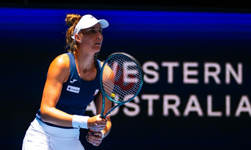 Bia Haddad, de camiseta azul e saia e boné branco, com a raquete na mão em frente a um backdrop escrito "Western Australia"; ela está na semifinal do WTA 500 de Adelaide, ao lado de Taylor Townsend