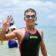 Henrique Figueirinha sorri para foto, em traje de banho, com mar ao fundo, após competir nas águas abertas; ele e Pedro Farias disputaram os 10km no Mundial de Doha