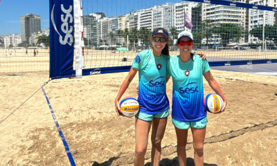 Talita e Taiana pousam para foto com a camisa do Botafogo em frente à quadra de areia; elas estão juntas no Circuito Brasileiro de vôlei de praia, com início em Campo Grande