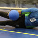 André Dantas está na ala esquerda e cai para o lado na defesa da bola, que atinge a altura de suas pernas, durante treino. Ele veste calça preta e camisa de manga longa azul com detalhes em verde. Foto: Renan Cacioli/ CBDV.