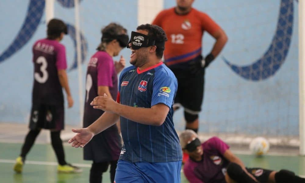 Guegueu, que veste camisa azul da Apadevi, sorri enquanto comemora um de seus dois gols na vitória sobre a Apid pelo Regional Nordeste de futebol de cegos (Foto: Renan Cacioli/CBDV)