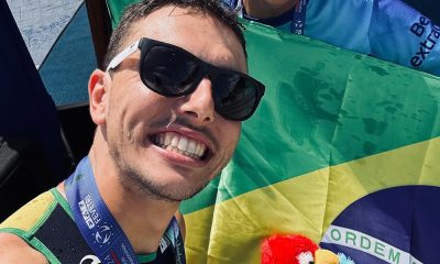 Na imagem, Kauê Willy em selfie com a bandeira do Brasil ao fundo.