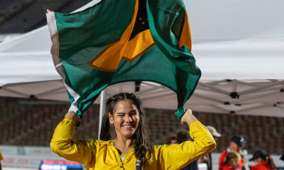Wanna Brito sorri e segura a bandeira do Brasil após medalha de ouro no lançamento de club no Mundial de Kobe