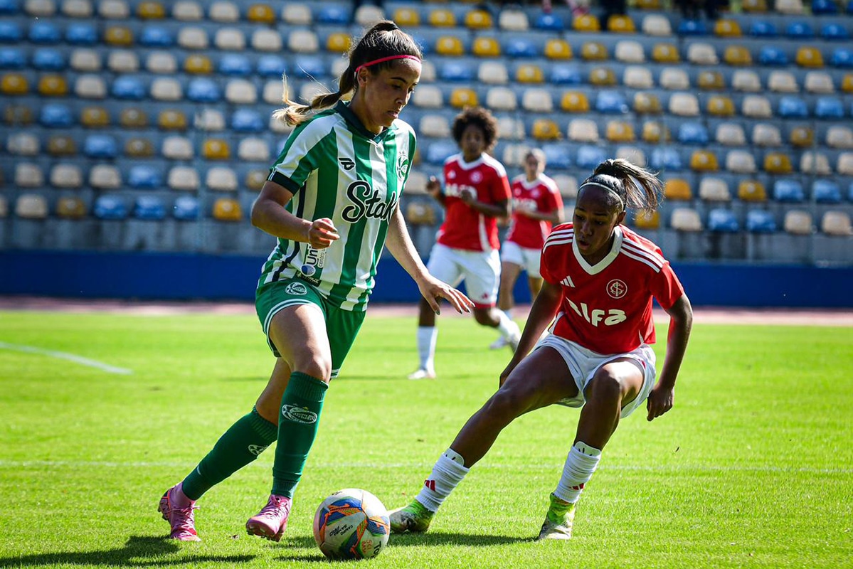 Na imagem, jogadora do Juventude avançando com a bola contra a marcação Colorada.