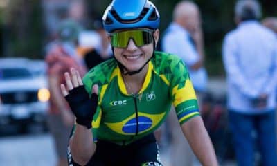 Na imagem, Alice Melo dando tchau após completar prova em El Salvador ainda em cima de sua bicicleta.
