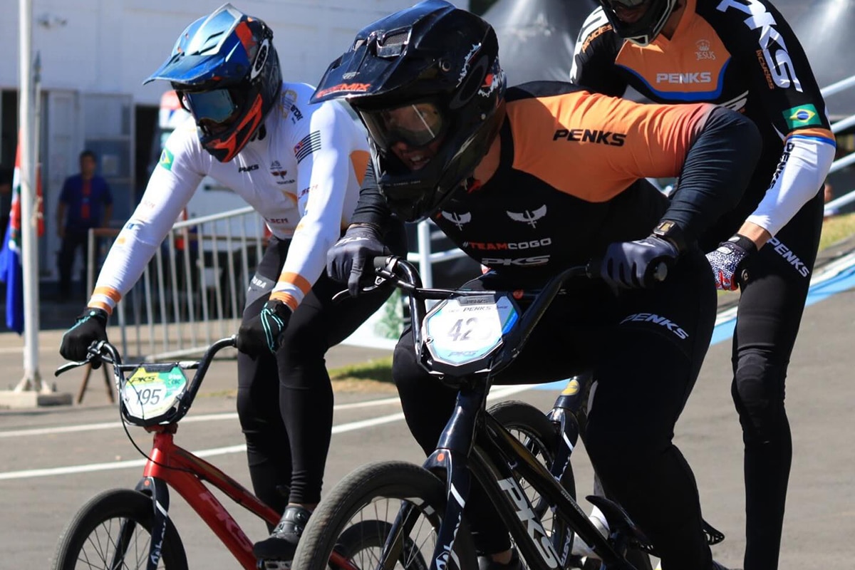 Na imagem, Bruno Cogo, de laranja e preto, durante a competição com sua bicicleta.