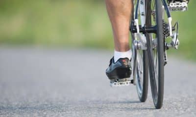 Ciclista pedalando em subida com foco no movimento das pernas e na fluidez da pedalada.