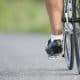 Ciclista pedalando em subida com foco no movimento das pernas e na fluidez da pedalada.